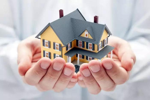 a person holding a model of a house in their hands