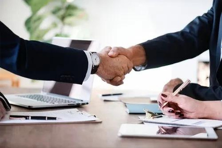 two business people shaking hands over a table